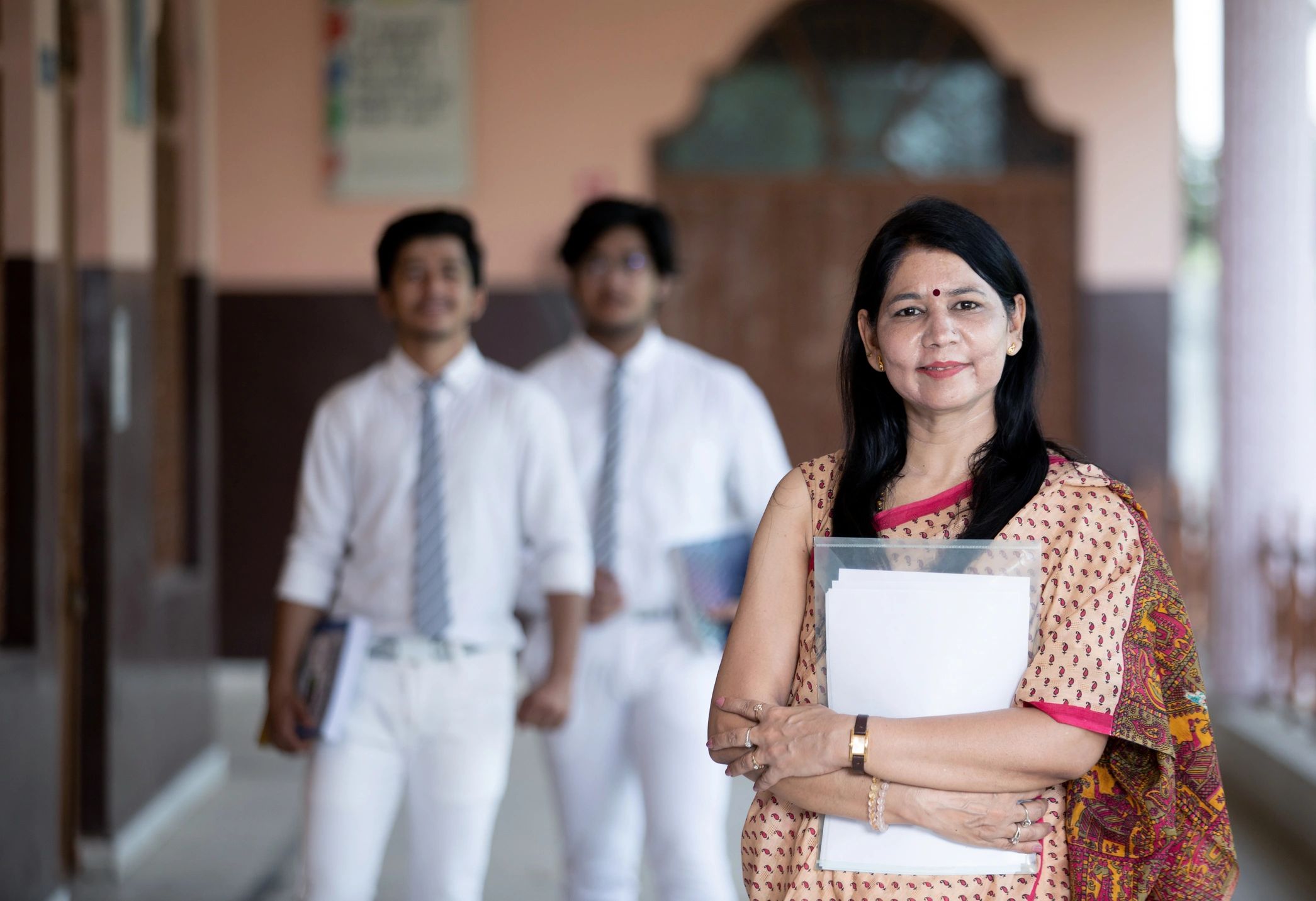 Indian teacher smiling with students in background
